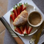 A cozy breakfast setup with croissant, strawberries, and coffee on a magazine.