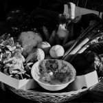 A rustic basket of fresh vegetables displayed on a wooden table in Tuscany, Italy.