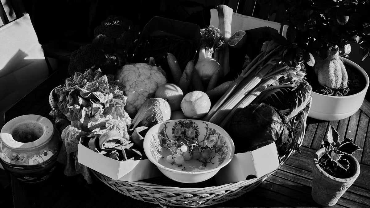 A rustic basket of fresh vegetables displayed on a wooden table in Tuscany, Italy.