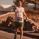 A cheerful man runs down a city street during a marathon, exuding energy and determination.