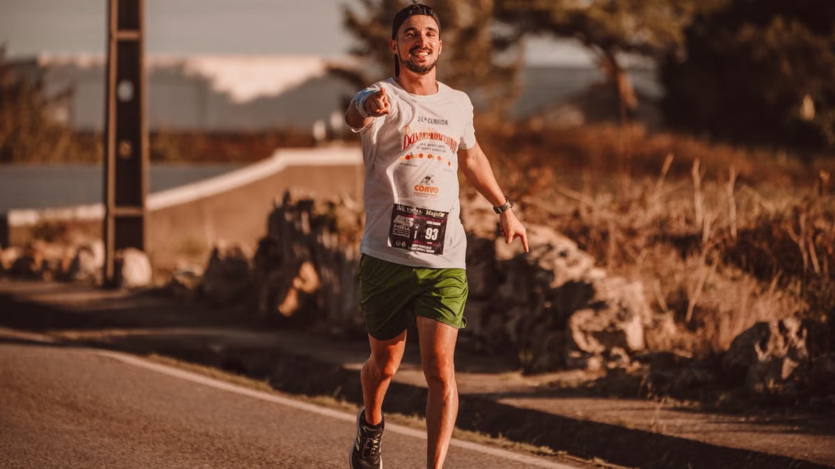 A cheerful man runs down a city street during a marathon, exuding energy and determination.
